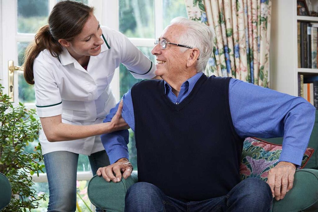 A social worker sits with an elderly resident at a table, listening attentively and offering a reassuring presence.