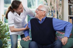 A social worker sits with an elderly resident at a table, listening attentively and offering a reassuring presence.